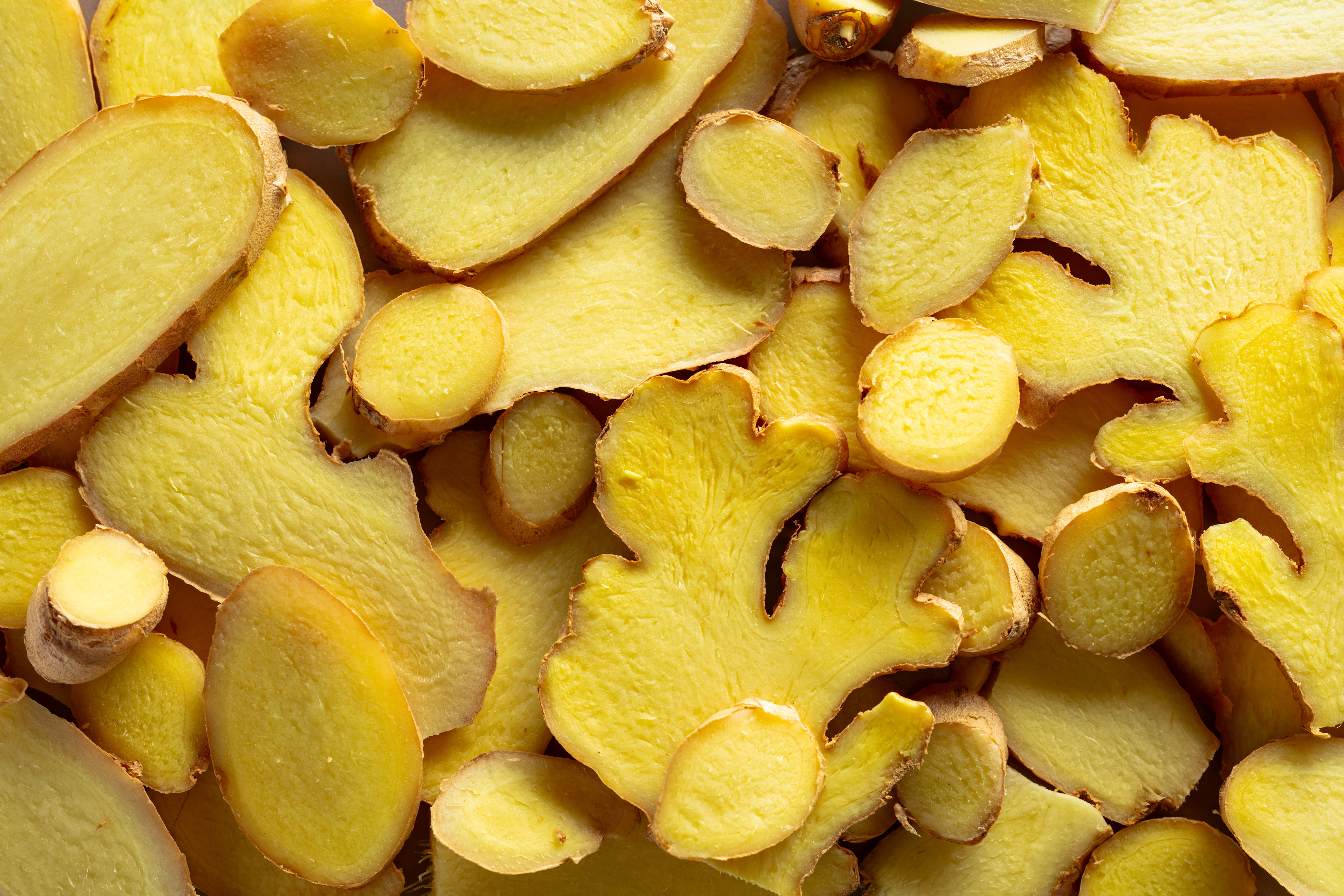 Fresh ginger root on a cutting board with a cup of ginger tea